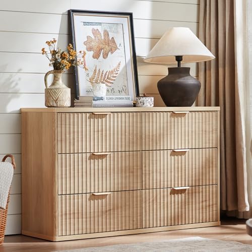 Wooden dresser with decorative items including a lamp, vase, and framed picture in a room setting.