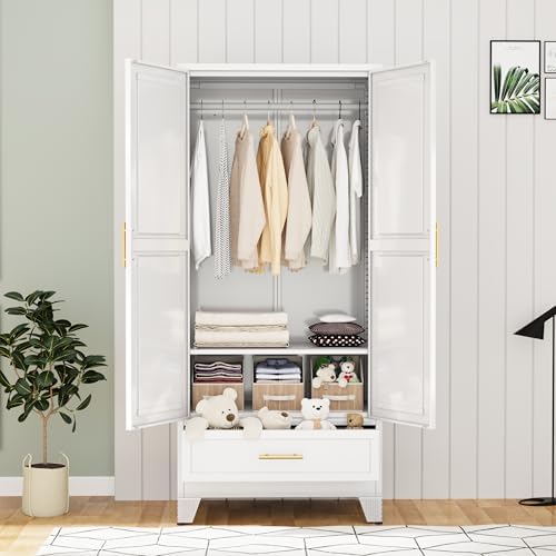 A white three-door wardrobe with gold handles, shown open in a styled bedroom setting. The wardrobe contains hanging clothes, folded bedding, storage bins, and a plush toy on the drawer.