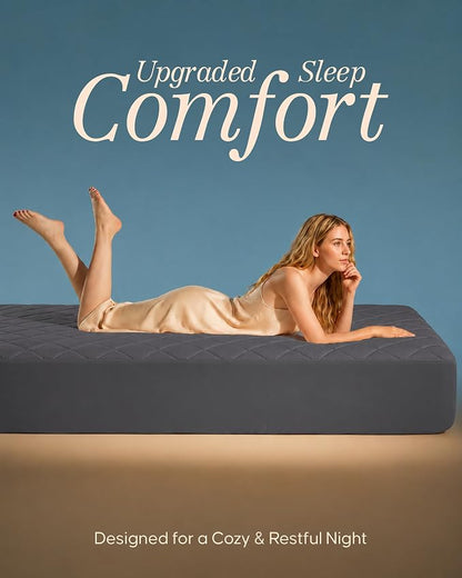 A woman in a beige slip dress reclines on a dark gray mattress against a blue background, with the text 'Upgraded Sleep Comfort' at the top and 'Designed for a Cozy & Restful Night' at the bottom.