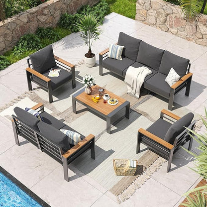 Outdoor patio furniture set with gray cushions and wooden accents on a stone patio.