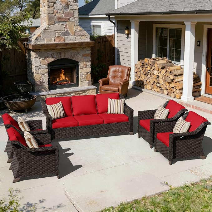 Outdoor patio set with red cushions in front of a stone fireplace.