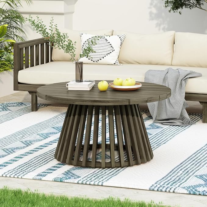 Outdoor setting with a wooden coffee table, sofa, and decorative items on a patio.