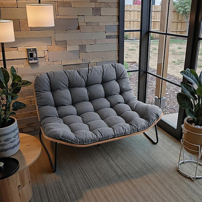 Gray cushioned chair in a room with a stone wall and large window.